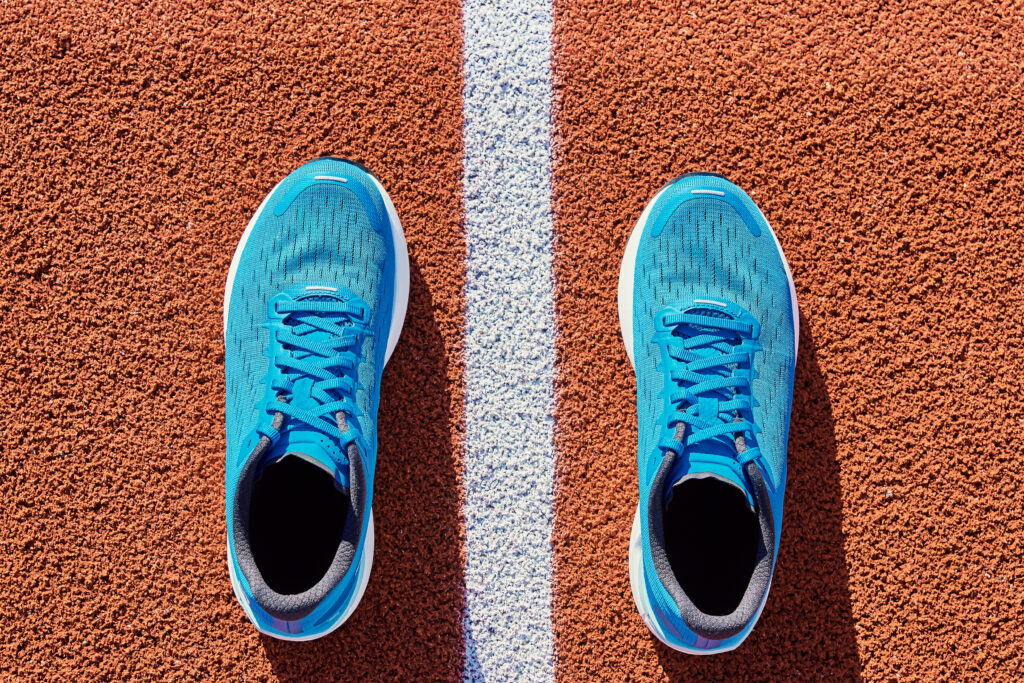 Top view of blue male running sneakers near start line at stadium track.